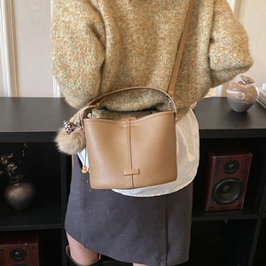 Detail of camel bucket bag with textured lychee leather and leopard print bow charm