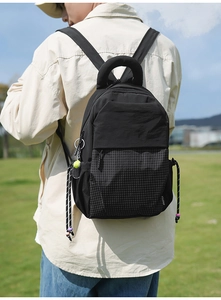 Detail of black sports backpack with ring handle, checkered pattern and tennis charm