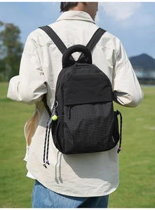 Detail of black sporty backpack with plaid panel, tennis charm, and bead drawstring