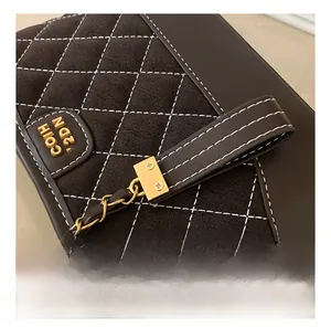Detailaufnahme der dunkelbraunen Wildledernähte und des Goldlogos auf der Beuteltasche