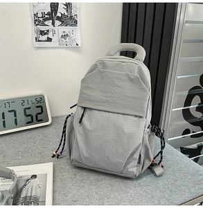 Detail view of the gray nylon backpack with checkered pattern and side drawstring pocket