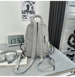 Detail of the light grey multifunctional backpack featuring thick top handle and side pocket