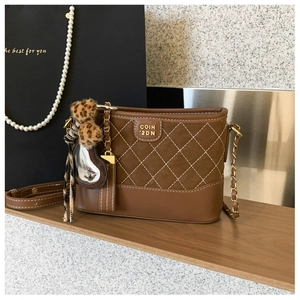 Detailansicht der braunen gesteppten Beuteltasche mit Leoparden-Bommel und Goldkette