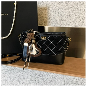 Detail einer schwarzen Stepptasche mit dekorativen Herzanhängern und goldenem Metalllogo