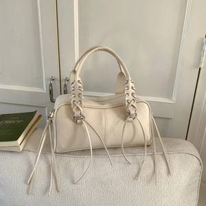 Detail of off-white leather tote bag featuring eyelet weaving and long decorative straps