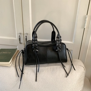 Detail of black matte leather tote bag with unique eyelet and long tassel fringe handles