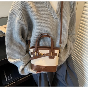 Dettaglio della borsa a secchiello bicolore panna e marrone con fibbia in metallo e pelle