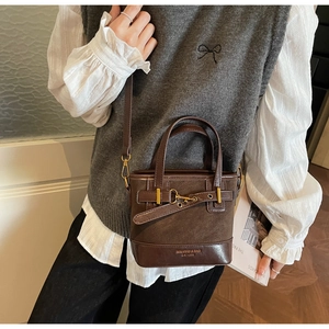 Dettaglio della borsa a secchiello vintage in pelle marrone con fibbia e tracolla