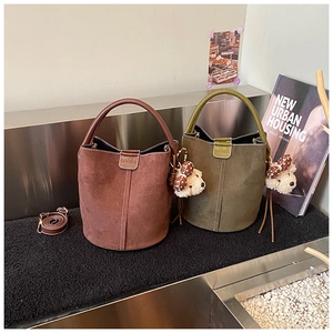 Detail der Vintage-Eimer-Tasche aus mattem Wildleder mit Magnetverschluss und Anhänger