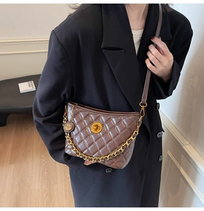 Detail of quilted brown patent leather bucket bag with gold chain and circular swivel lock