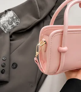 Détail latéral d'un sac à main rose avec boucle dorée en D et finition cuir lisse