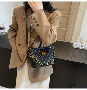Detail showing the quilted black leather texture with gold metal chain and round lock