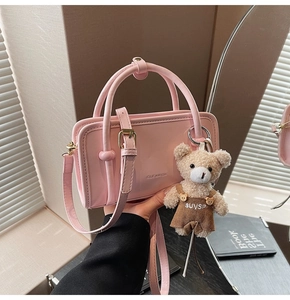 Détail du sac à main en cuir verni rose avec un pendentif ours en peluche sur le côté