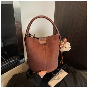 Detailansicht der braunen Wildleder-Beuteltasche mit Plüschbären-Anhänger und Schleifen-Deko