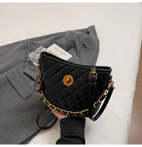 Detail of black quilted bucket bag featuring a gold twist lock and chunky chain strap
