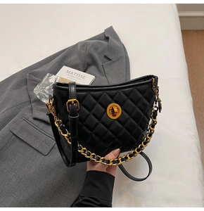 Detailed shot of black quilted bucket bag with gold chain strap and rotary lock clasp