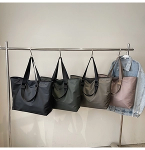 Détail de grands sacs fourre-tout en nylon en quatre couleurs sur un support minimaliste