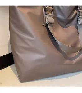 Détail du sac fourre-tout en nylon marron foncé avec poignée renforcée et boucle métallique