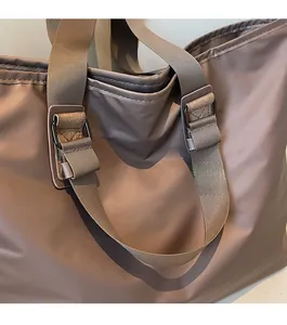 Détail rapproché des ferrures métalliques et du tissu satiné brillant sur le sac cabas