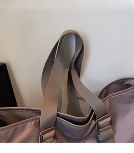 Détail de la bandoulière en nylon dense et boucle en métal d'un grand sac fourre-tout