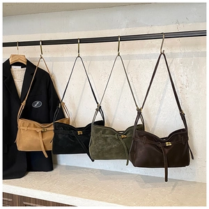 Elegantes bolsos de hombro en ante de tonos tierra colgados en un estudio minimalista