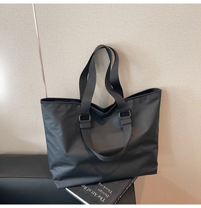 Gros plan d'un sac cabas noir minimaliste avec large bandoulière en nylon et fini mat