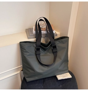 Détail du sac fourre-tout vert armée avec bandoulière noire réglable dans un cadre domestique