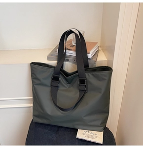 Détail d'un grand sac cabas vert foncé avec sangle large réglable et tissu en nylon lisse