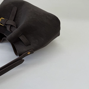 Detailed view of brown leather handbag featuring golden buckles and metal rivets