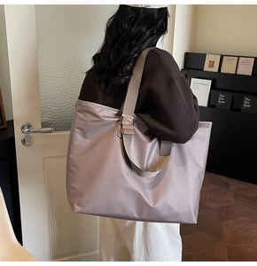 Vue détaillée du grand sac cabas rose poudré en nylon soyeux porté par un mannequin femme