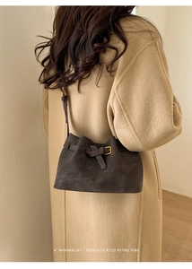 Detail of a brown suede vintage crossbody bucket bag with elegant gold buckle strap
