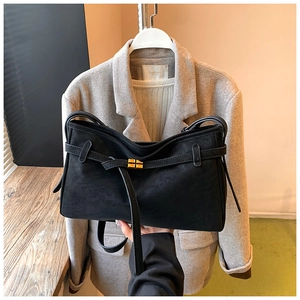 Detalle del bolso tipo cubo en ante negro con elegante cierre de giro dorado