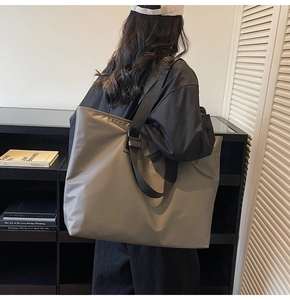Grand sac fourre-tout gris-vert porté par un mannequin dans un intérieur moderne