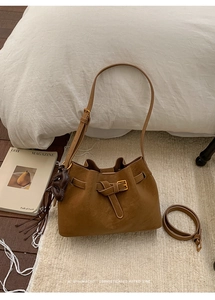 Detail of vintage brown suede bucket bag with leather bear charm and spare shoulder strap