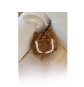 Detail of brown suede bucket bag with white faux shearling trim beside an open book