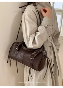 Detail of dark brown retro baguette bag with woven leather drawstring and metal rings