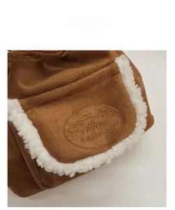 Detail of brown suede bucket bag featuring mika embroidery and white faux fur trim edge
