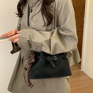 Retro black faux suede bucket bag with heart tassel charm in a lifestyle interior setting