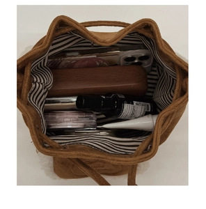 Interior view of brown suede bucket bag showing spacious storage for makeup and phone