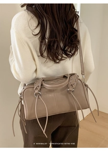 Detail of vintage baguette bag with woven handles and long tassels on a stylish model