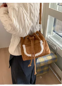 Detailed view of brown faux suede bucket bag with plush white fur trim and drawstring closure