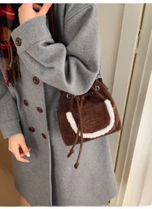 Detailed shot of brown suede bucket bag with white fleece trim and drawstring closure