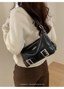 Detailansicht einer schwarzen Retro-Schultertasche mit Schnallen an der Schulter