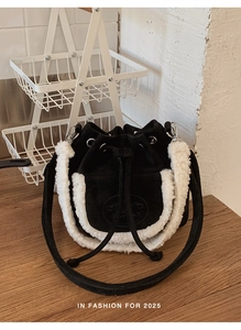 Close-up of black suede bucket bag featuring white faux fur trim and drawstring detail