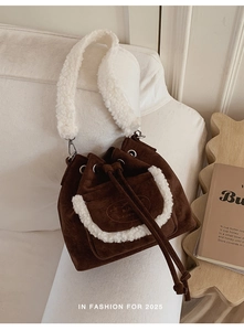 Detail view of brown suede bucket bag with white fleece trim and soft plush shoulder strap