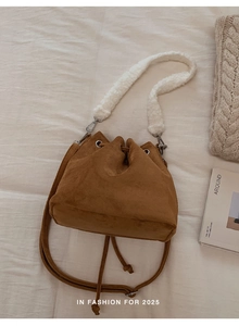 Detail of brown faux suede bucket bag featuring a soft white plush faux shearling shoulder strap