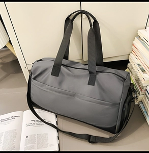 Detalle de la bolsa de viaje gris y negra con asas dobles y correa de hombro ajustable