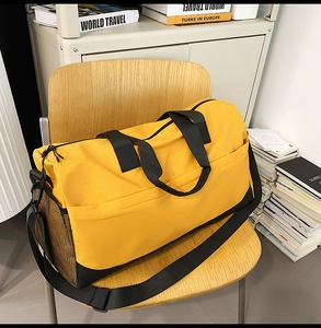 Detalle de bolsa de viaje amarilla con bolsillo lateral de malla y correa ajustable en silla