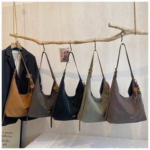 Eleganti borse tote in cinque colori appese a un ramo con nappine decorative alla moda