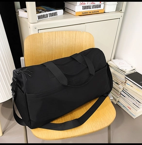 Detalle de bolsa de viaje negra con correa ajustable sobre una silla de madera
